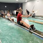 teens training on rowing machines indoors