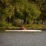 young man paddling in kayak in distance close to shoreline