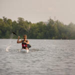 distant shot of young man in kayak paddling toward us