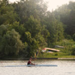 young man paddling in kayak with trees in background