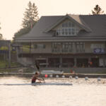 young man in kayak with yacht club building in background