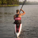 young man paddling away from us in kayak