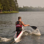 young man paddling away from us in kayak