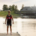 young man standing on wooden dock holding paddle