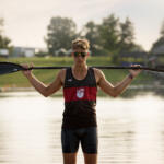 young man in tank top holding rowing paddle across his shoulders