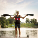 young man in tank top holding rowing paddle across his shoulders