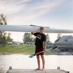 young man holding a kayak on his shoulder