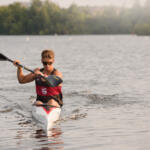 young man in kayak paddling toward us