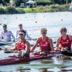 three athletes rowing in single kayak