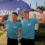 two young men in teal shirts flexing biceps